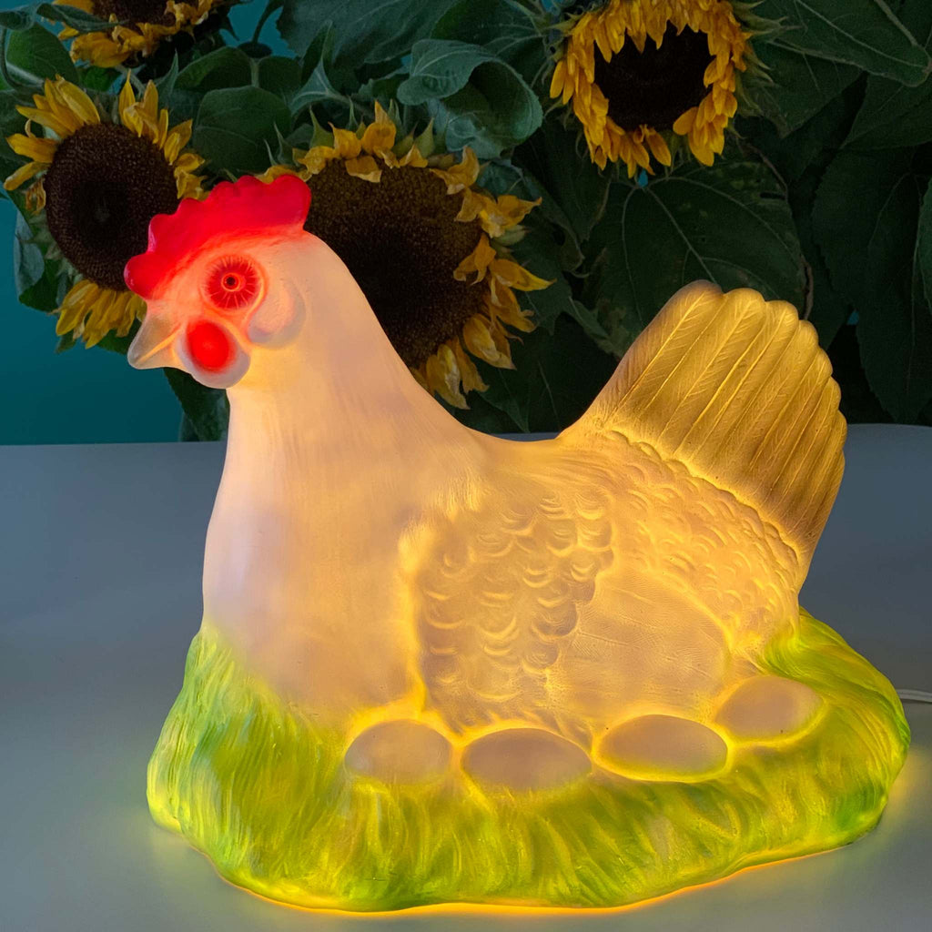 Foto viser en lampe med en høne der ligger på æg i sin rede. Med LED lys